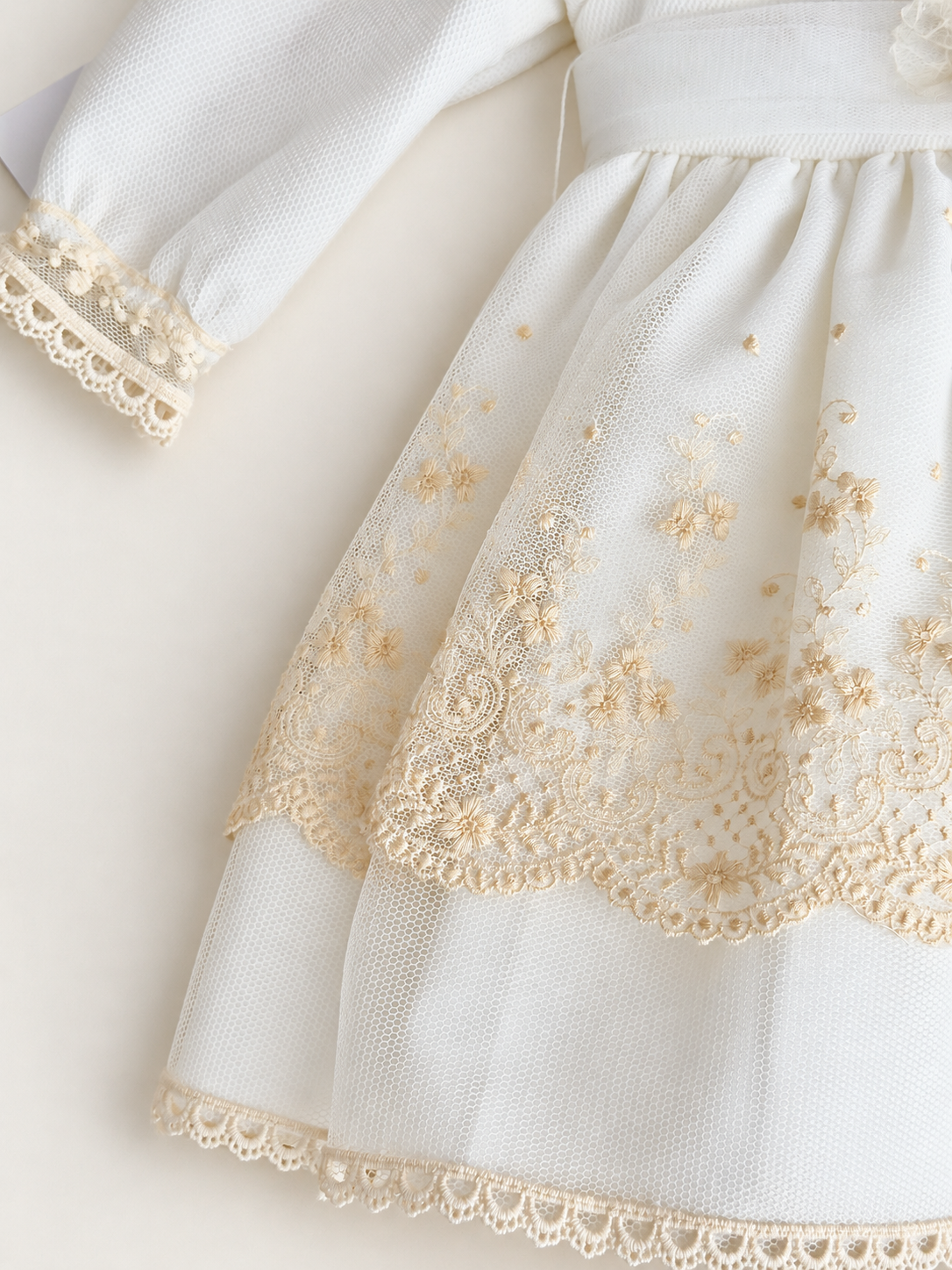Abito Charo con ricami crema e fiore rosa su sfondo bianco caldo