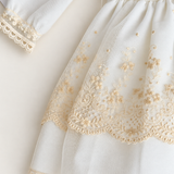 Abito Charo con ricami crema e fiore rosa su sfondo bianco caldo
