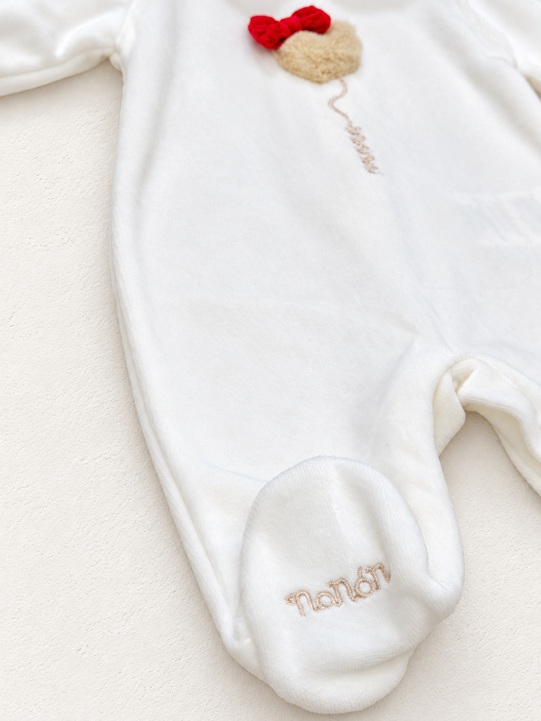 Tutina Nanan, dettaglio su sfondo bianco caldo naturale